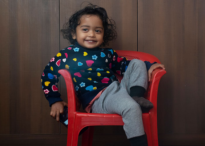 Toddler with curly hair sitting casually on a red chair, illustrating creepy things kids said that scared parents.