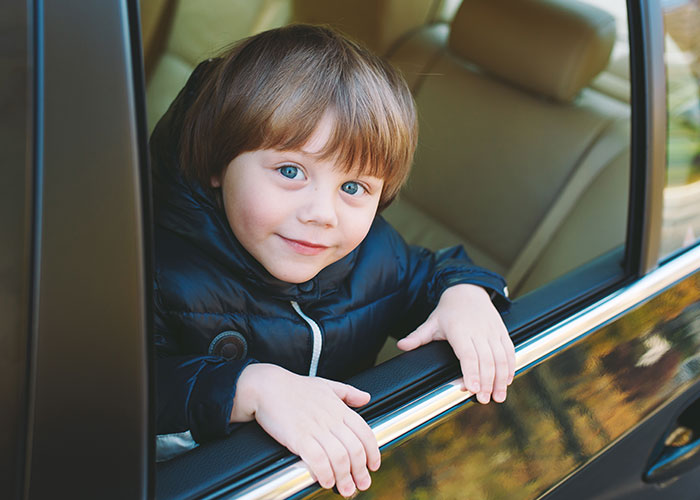 Young boy with blue eyes and brown hair looking out car window, representing creepy things kids said that scared parents.