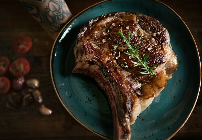 Grilled steak on a blue plate garnished with rosemary, illustrating habits affecting mental and physical health long-term.