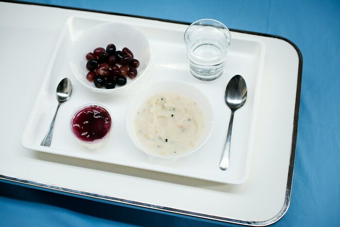 Hospital meal tray with soup, jelly, fruit, and water illustrating challenges ER staff face with patients complicating their work.