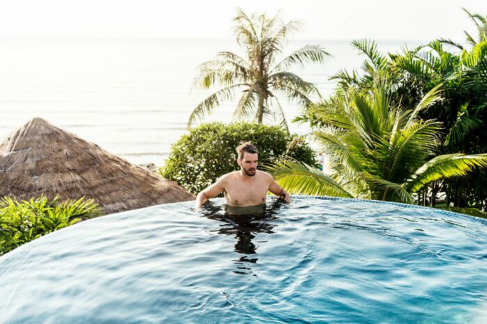 Man in infinity pool surrounded by palm trees, capturing a moment instinctively feeling something was wrong outdoors.