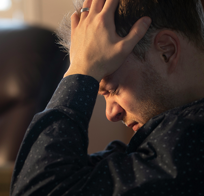 Upset man holding head, frustrated over dad not passing on craft skills while half-brothers start craft business. Upset man holding head, frustrated over dad not passing on craft skills while half-brothers start craft business.