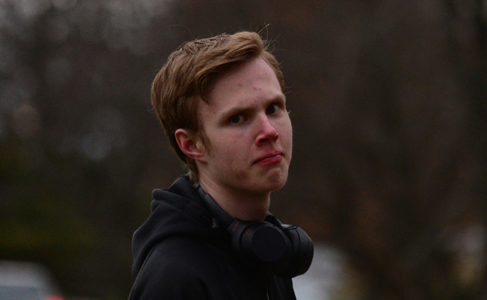 Young man upset outdoors, wearing black hoodie and headphones, expressing frustration over craft skills and family business. Young man upset outdoors, wearing black hoodie and headphones, expressing frustration over craft skills and family business.