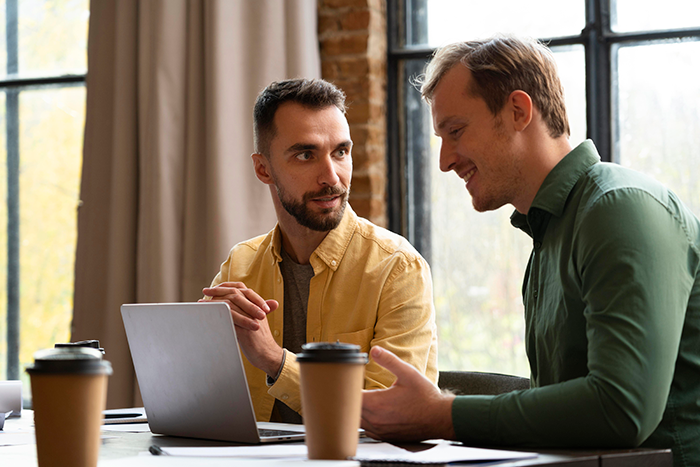 Two men collaborating at a table with laptops and coffee, symbolizing craft skills and business partnership. Two men collaborating at a table with laptops and coffee, symbolizing craft skills and business partnership.