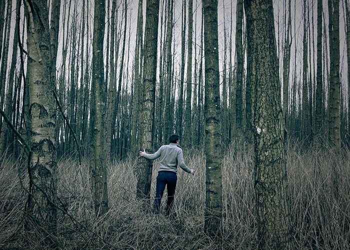 Person walking through dense forest, illustrating the risks of survival hacks that can be dangerous and useless.
