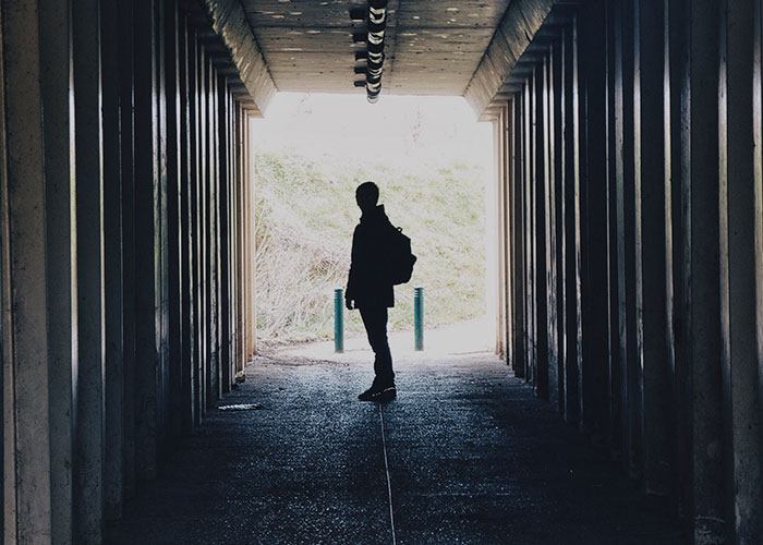 Silhouette of a person with backpack standing in a tunnel, illustrating survival hacks that can be dangerous and useless.