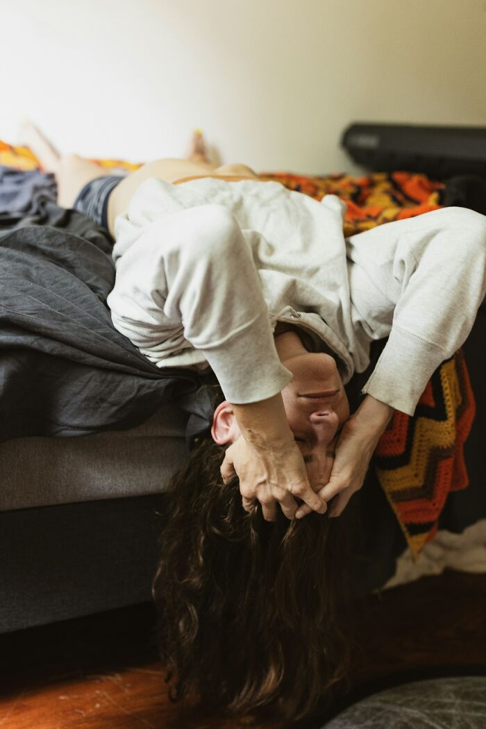 Person lying on bed upside down with hands on head, conveying stress and fatigue related to chefs stopping cooking professionally.