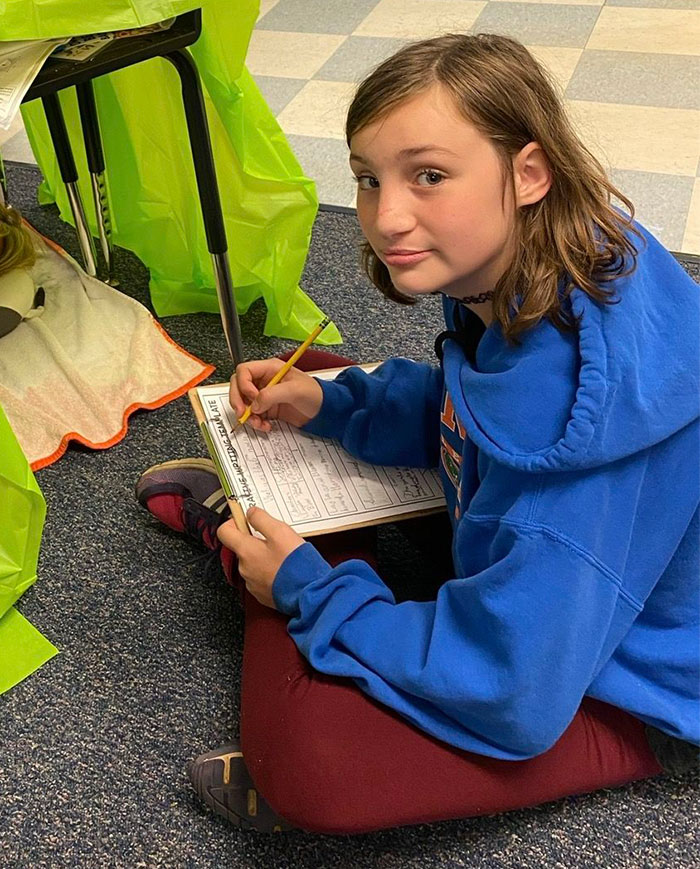 Teen girl sitting on floor writing on paper, illustrating teen boys setting 14YO girl on fire over revenge feelings.