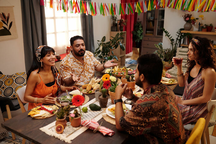 Four people enjoying a multicultural meal together, sharing stories about dating outside of their culture.