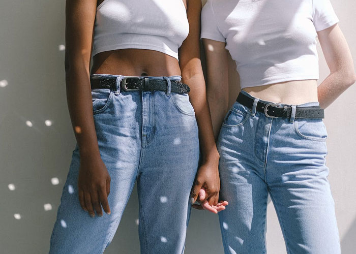 Two women holding hands wearing casual white tops and blue jeans, representing a gay daughter and mom relationship. Two women holding hands wearing casual white tops and blue jeans, representing a gay daughter and mom relationship.