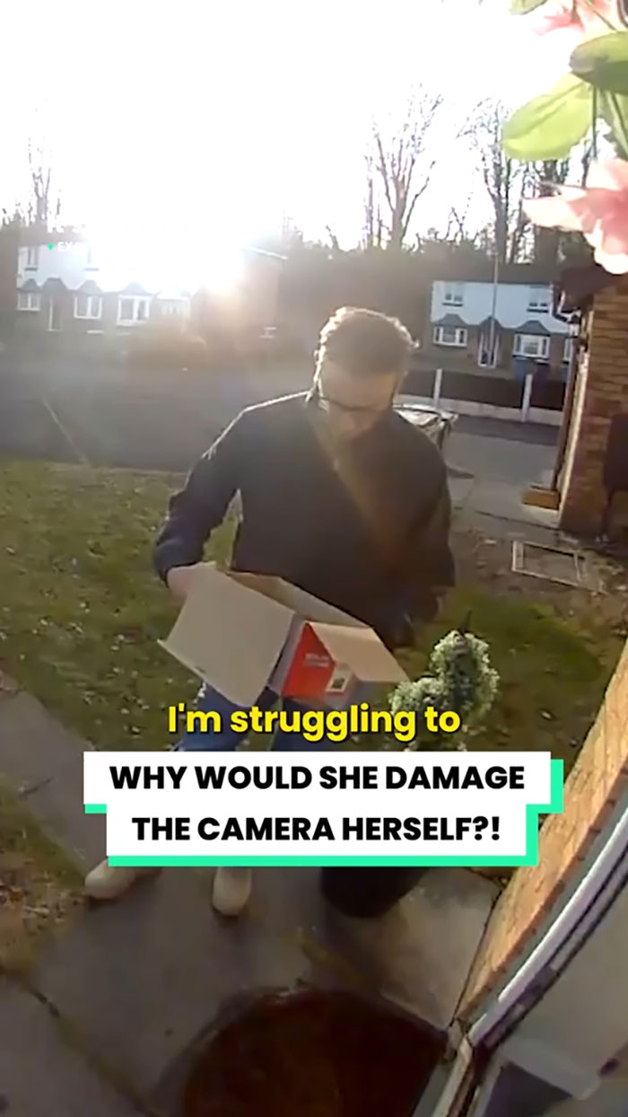 Delivery driver holding a damaged Christmas gift box outside a house, caught on security camera footage.