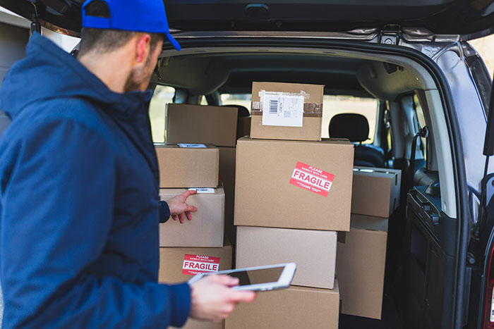 Delivery driver checking fragile packages in the back of a van related to woman&rsquo;s shattered Christmas gift claim.