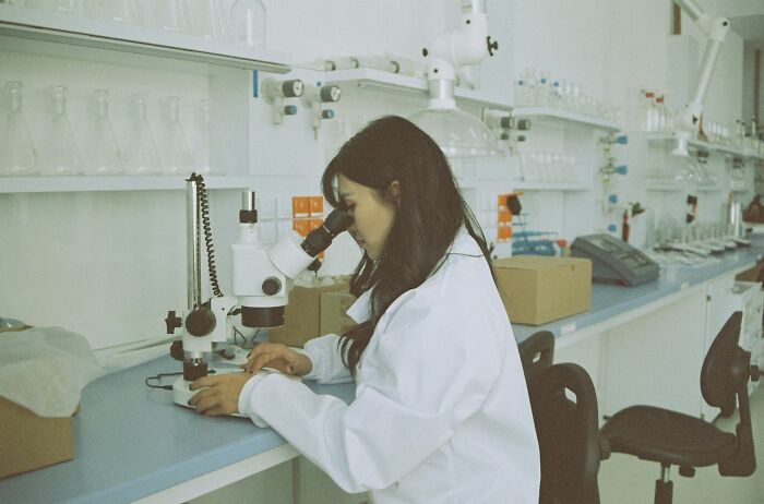 Woman in lab coat using a microscope in a laboratory, symbolizing people online sharing crazy facts they know.