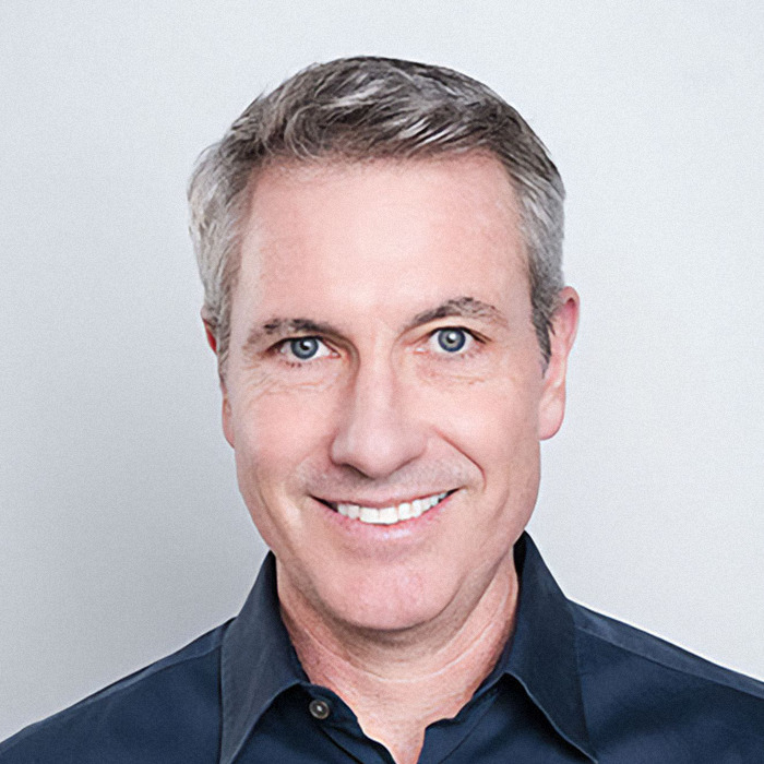 Headshot of a smiling man with gray hair and blue eyes wearing a dark shirt in a neutral background for HR exec Kristin Cabot.