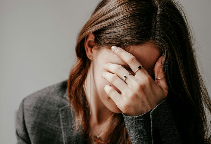 Woman covering face with hand, appearing distressed, representing disturbing things found in homes of normal people.