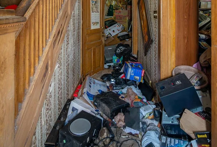 Cluttered hallway filled with trash and discarded items, showcasing disturbing things found in homes of seemingly normal people.