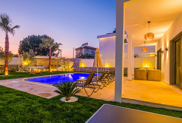 Modern home exterior with pool and lounge chairs, showcasing disturbing things found in homes of seemingly normal people at dusk.