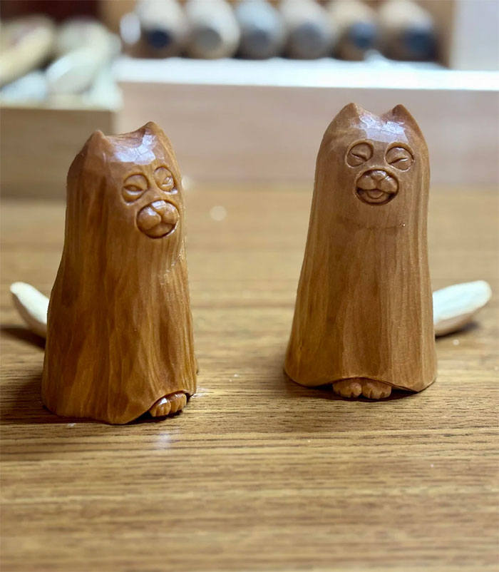 Two small wooden animal carvings with detailed faces and paws on a wooden surface, showcasing cool handmade art.