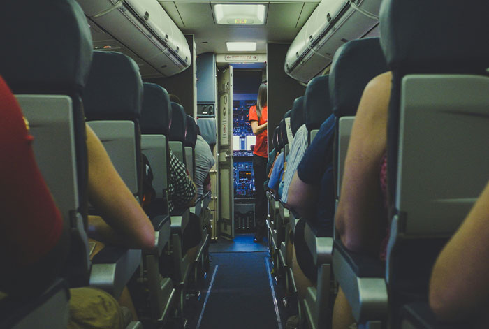 Passengers seated inside an airplane cabin as the flight takes off with a focus on an emergency medical story.
