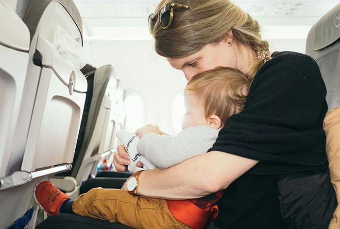 Woman comforting baby on airplane seat, illustrating a medical emergency when the flight took off and lungs collapsed.