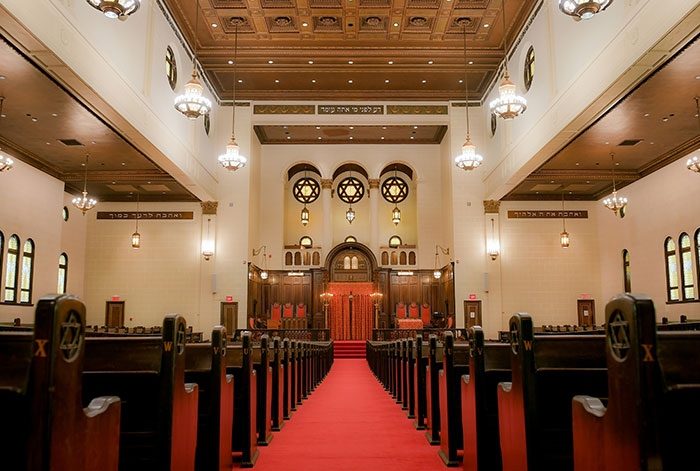 Interior of a synagogue with wooden pews and a red carpet aisle under ornate ceiling lights, highlighting incredible emergency stories.