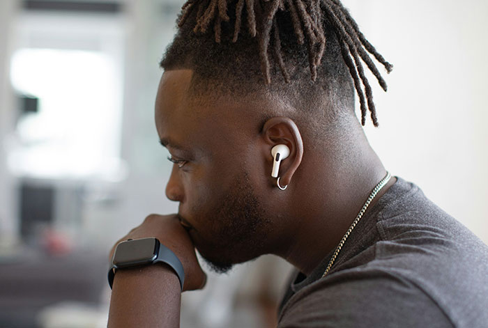 Young man wearing wireless earbuds and smartwatch, deep in thought, illustrating dramatic flight lung collapse story.