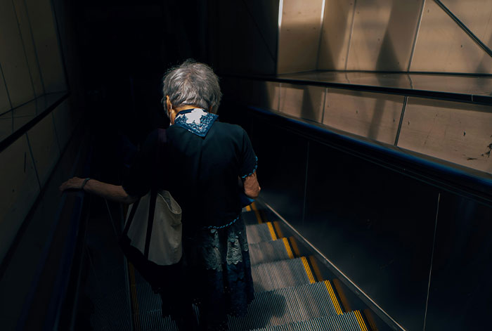 Elderly woman descending an escalator in a dimly lit space, evoking a medical emergency and lung collapse scenario.