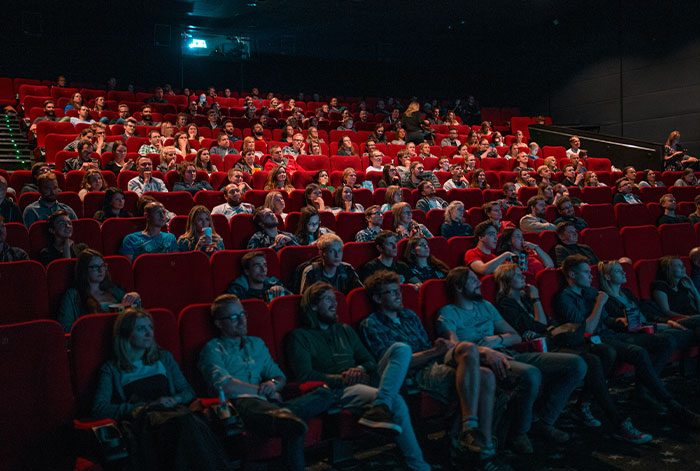 Audience watching a movie in a dark theater, focused on a story about lungs collapsing during flight medical emergency.