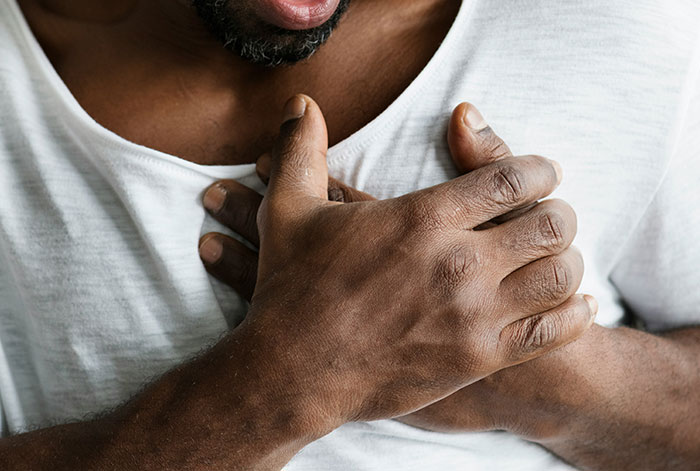Man clutching chest in pain, illustrating lung collapse during flight emergency medical story scenario