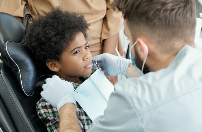 Child patient sitting in dental chair while doctor wearing gloves addresses common health concerns people freak out about but are normal.