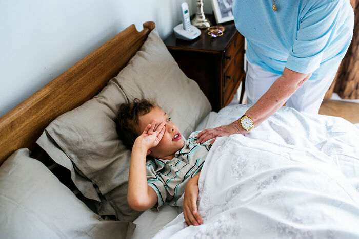 Child resting in bed while an adult checks on them, illustrating common health concerns that are actually normal.