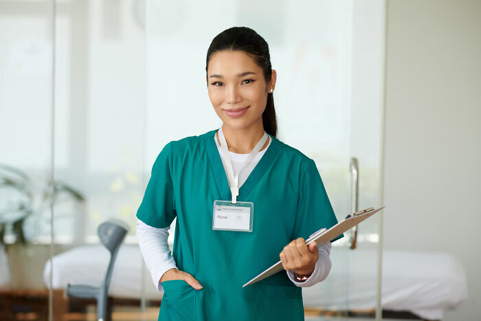 Young female doctor in green scrubs holding clipboard, representing common health concerns that freak people out but are normal.