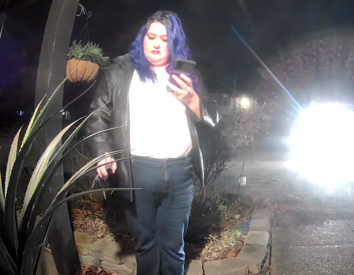 Woman with blue hair wearing a black jacket seen on a porch at night near plants and bright light source. Woman with blue hair wearing a black jacket seen on a porch at night near plants and bright light source.