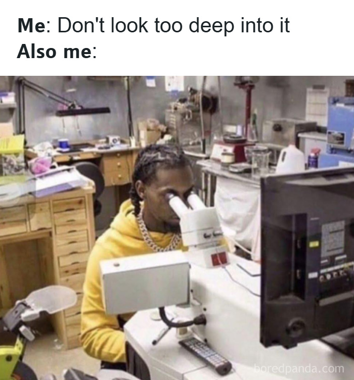 Man in a yellow hoodie intensely looking through a microscope in a cluttered lab, illustrating hilarious memes about stress relief.