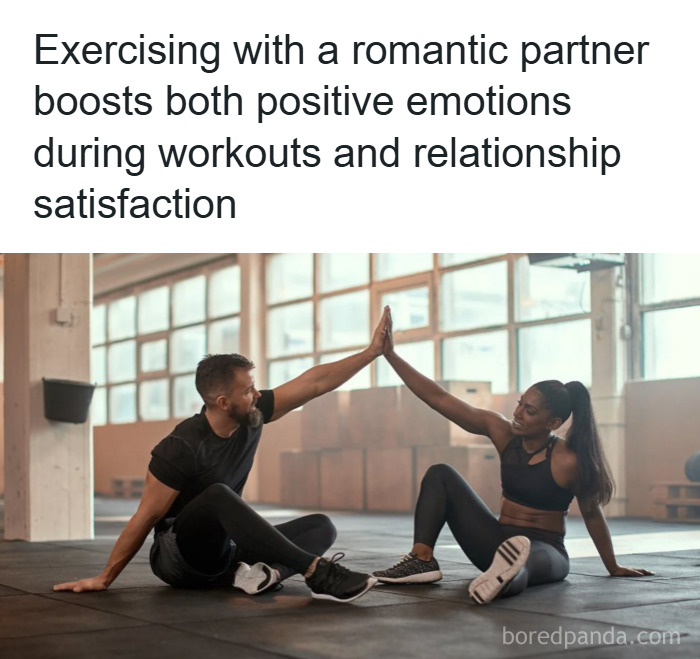 Couple exercising together indoors, sharing a high-five and enjoying positive emotions and relationship satisfaction.