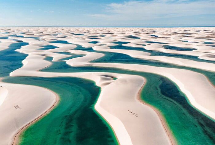 Aerial view of unique white sand dunes and turquoise water channels in a natural landscape that looks AI generated but is real.