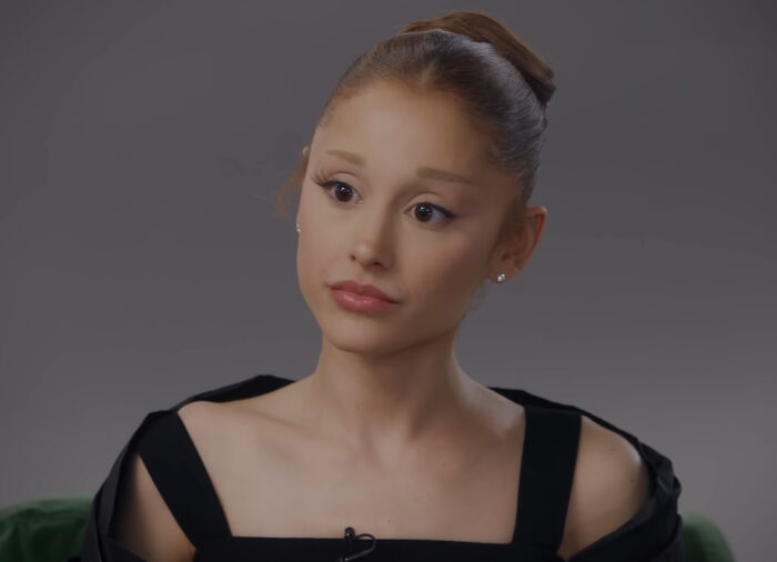 Ariana Grande in a black outfit during an interview as family member discusses her struggles and not being in a healthy place.
