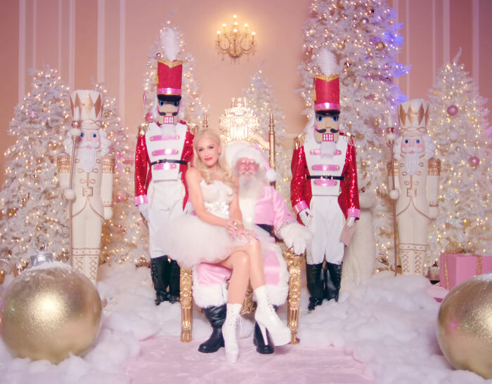 Gwen Stefani in a festive but controversial outfit at Rockefeller Tree Lighting with holiday decorations and nutcracker figures.