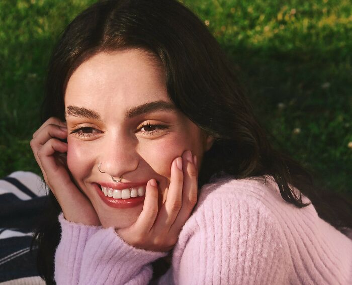 Young woman smiling outdoors, illustrating crazy things people have done to make their ex pine for them.