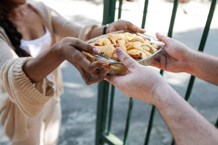Person handing over a dish of Thanksgiving leftovers to another person outdoors, illustrating entitled guest behavior. Person handing over a dish of Thanksgiving leftovers to another person outdoors, illustrating entitled guest behavior.