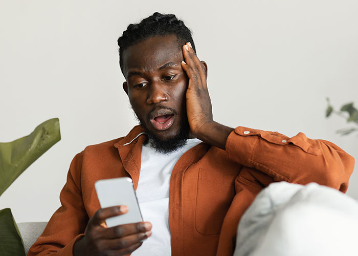 Man surprised and shocked looking at phone, reacting to unexpected message after fiancé disappeared years ago.