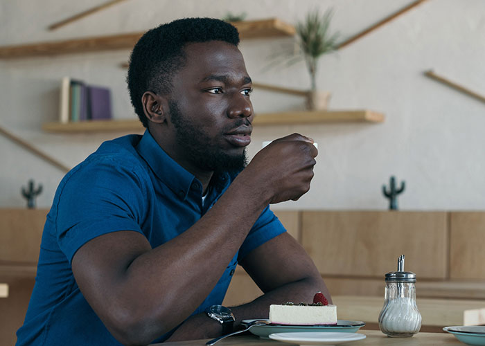 Man in blue shirt sitting thoughtfully at a table, symbolizing man left without closure after fiancé disappears before wedding.