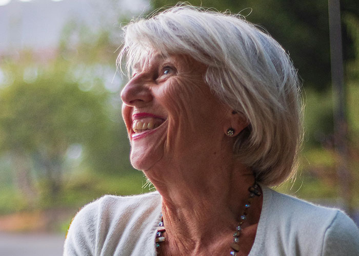 Smiling elderly woman outdoors reflecting on the moment they realized they are actually in a cult experience.