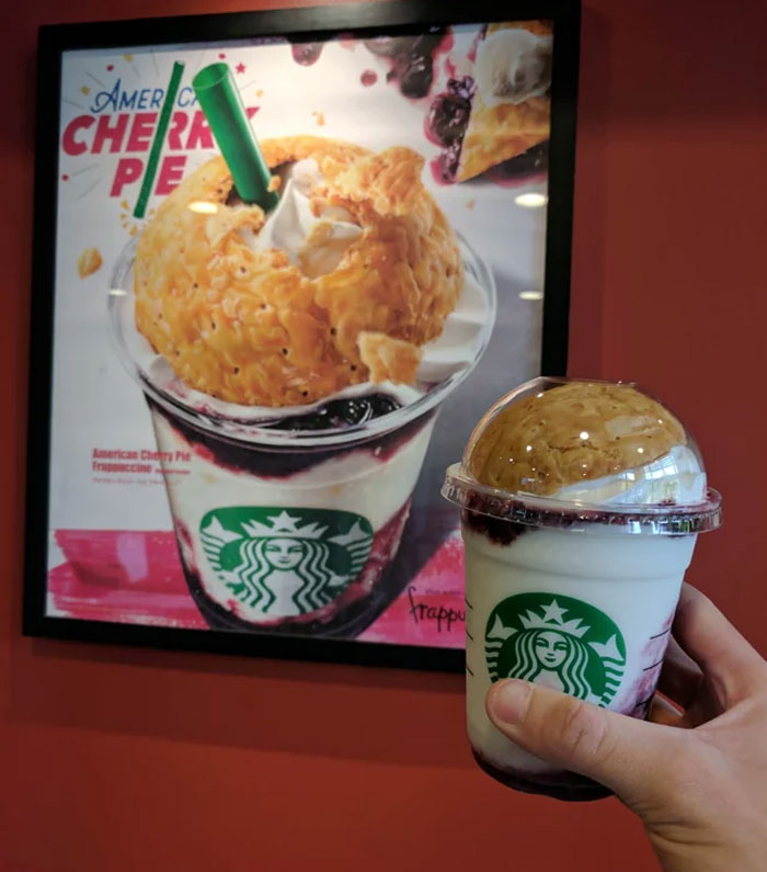 Hand holding Starbucks American Cherry Pie Frappuccino, showing expectations vs reality of the drink's appearance.