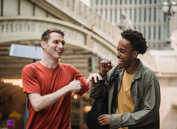 Two young men smiling and fist bumping outdoors, illustrating themes of family and overcoming shame and guilt.