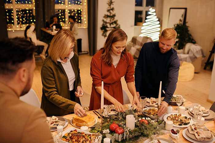 Family preparing holiday dinner in decorated dining room, reflecting Christmas hosting and family gathering challenges. Family preparing holiday dinner in decorated dining room, reflecting Christmas hosting and family gathering challenges.