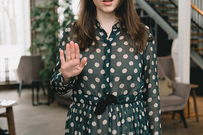 Woman in polka dot dress gesturing stop inside a house, symbolizing family tired of hosting ungrateful relatives for Christmas. Woman in polka dot dress gesturing stop inside a house, symbolizing family tired of hosting ungrateful relatives for Christmas.