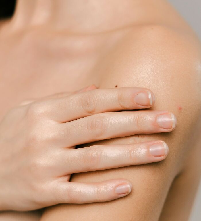 Close-up of a hand gently touching smooth shoulder skin illustrating interesting life facts about the human body.