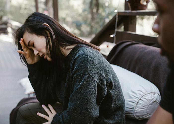 Woman looking distressed and deep in thought while sitting on a couch, related to fianc&eacute;e&rsquo;s unexpected request before wedding.