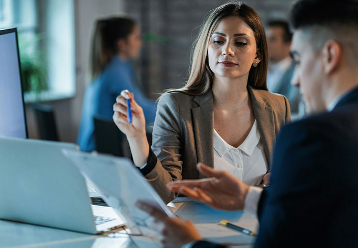 Woman reviewing legal documents with a man in an office, relating to restraining order against MIL after years of marriage.